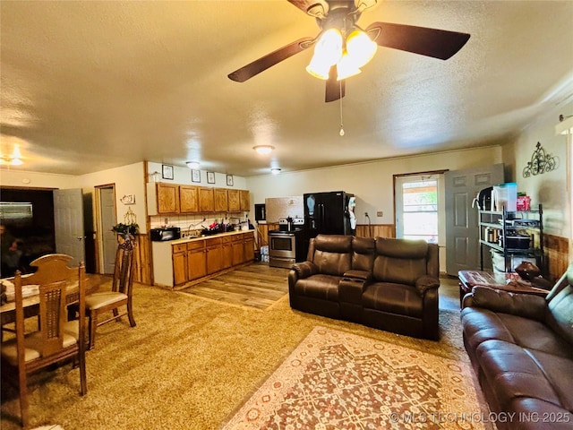 living area with light colored carpet, a ceiling fan, and a textured ceiling