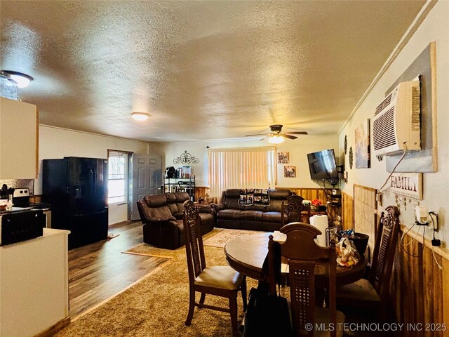 carpeted dining room featuring a wall mounted AC, a textured ceiling, and ceiling fan