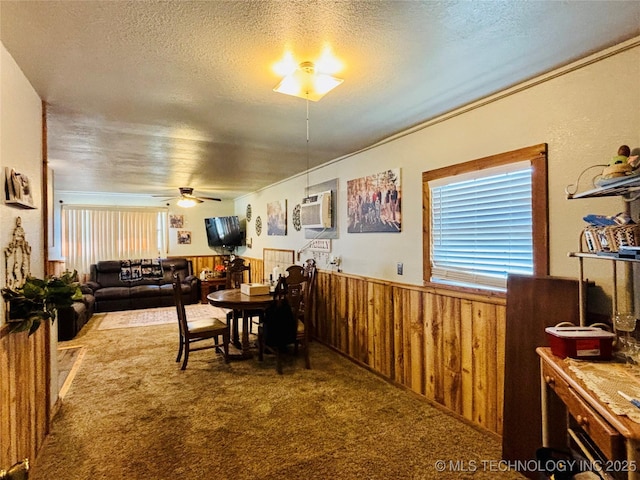 carpeted dining room featuring a wall mounted air conditioner, a textured ceiling, ceiling fan, and wainscoting