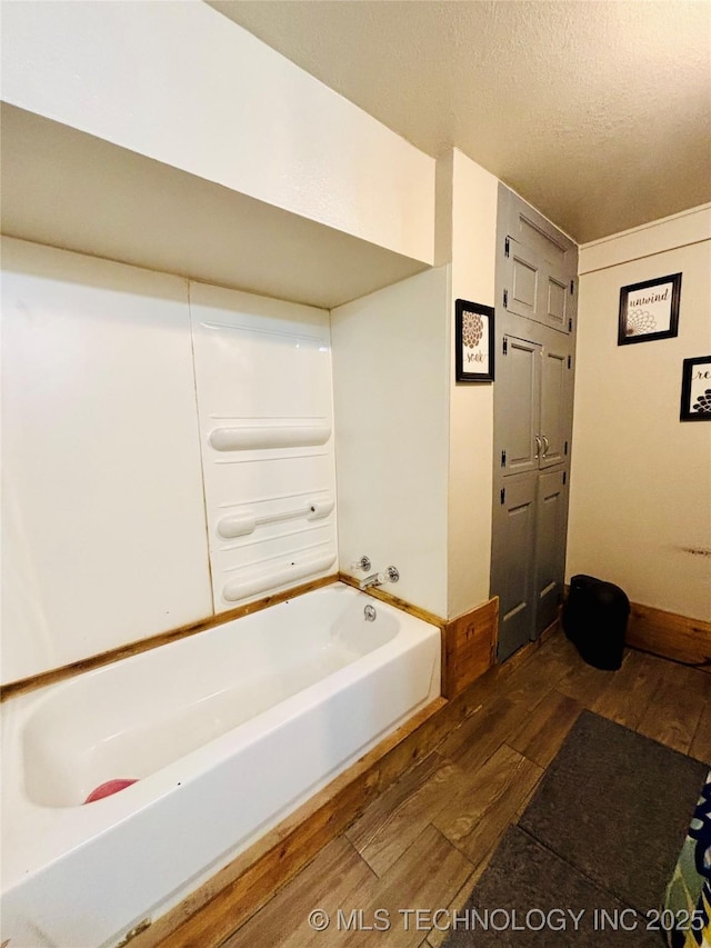 full bathroom with a bathtub, wood finished floors, and a textured ceiling