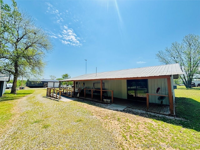 back of house featuring a lawn, an outdoor structure, and metal roof