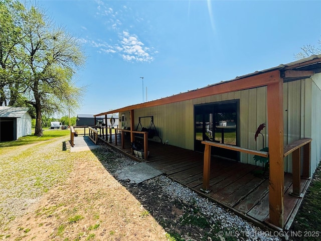 back of property with a wooden deck and an outbuilding