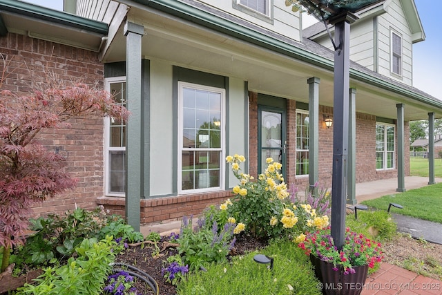 view of side of property featuring covered porch and brick siding