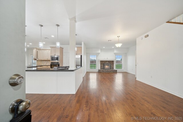 kitchen featuring dark countertops, appliances with stainless steel finishes, dark wood finished floors, open floor plan, and decorative backsplash