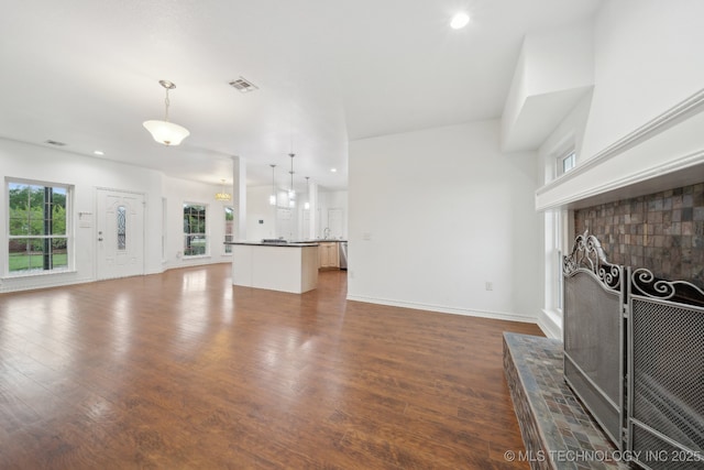 unfurnished living room featuring visible vents, a tiled fireplace, baseboards, dark wood-style floors, and recessed lighting