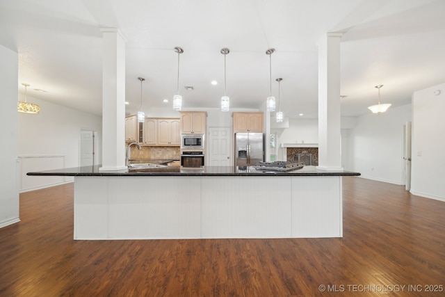kitchen with dark countertops, dark wood-type flooring, a sink, backsplash, and stainless steel appliances