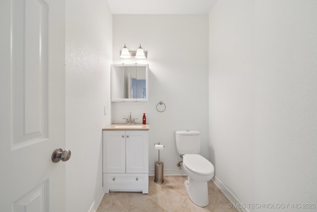 half bathroom with toilet, baseboards, tile patterned floors, and vanity