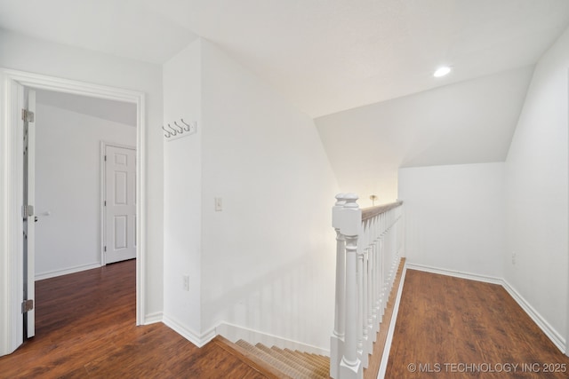 hallway with baseboards, an upstairs landing, wood finished floors, and lofted ceiling