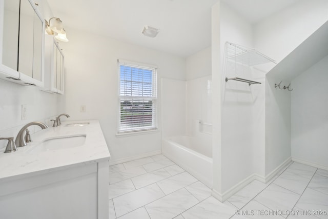 full bathroom with double vanity, baseboards, a sink, and marble finish floor