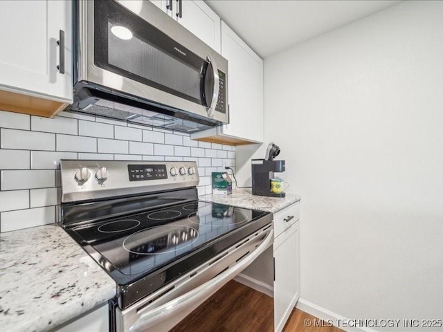 kitchen featuring white cabinets, decorative backsplash, wood finished floors, and appliances with stainless steel finishes