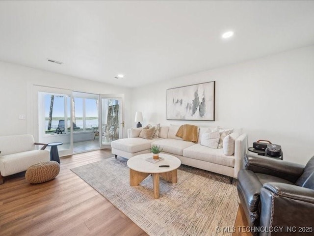 living area with recessed lighting, wood finished floors, and visible vents