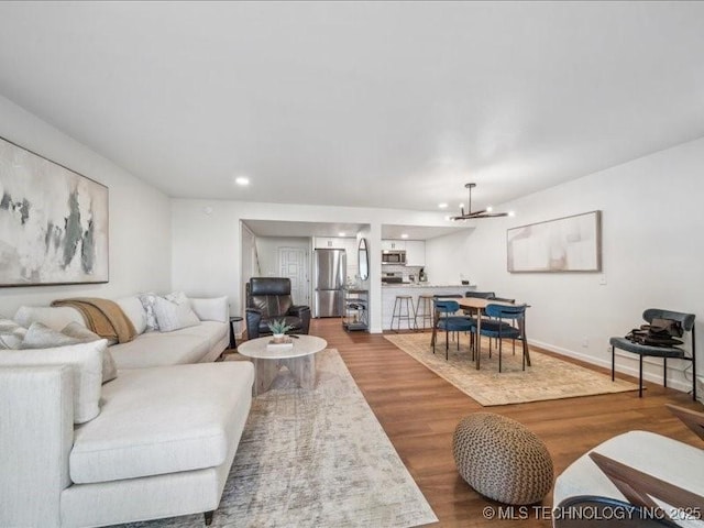 living room with baseboards, wood finished floors, a chandelier, and recessed lighting
