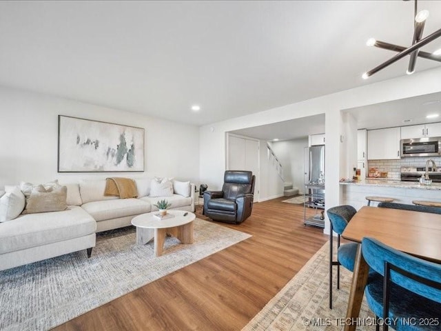 living room with baseboards, wood finished floors, recessed lighting, and stairway