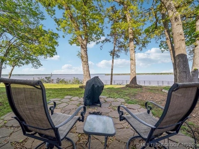 view of yard with fence, a patio area, and a water view