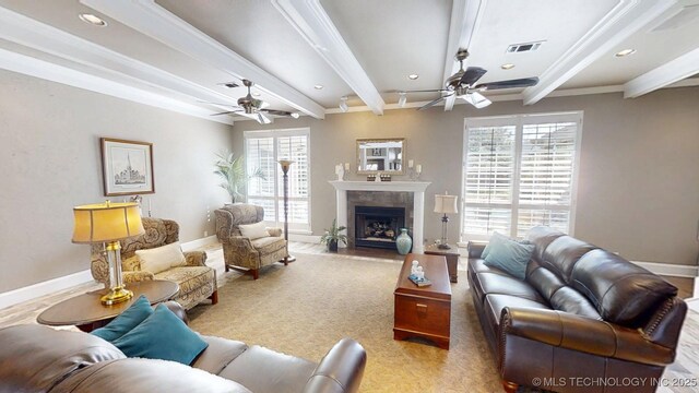 living room featuring ceiling fan, baseboards, a fireplace with flush hearth, beamed ceiling, and visible vents