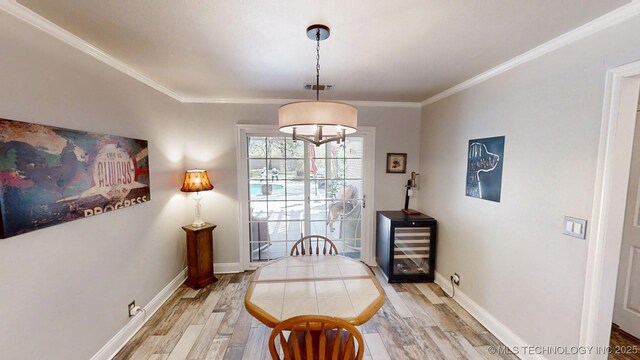 dining room featuring crown molding, baseboards, and light wood finished floors