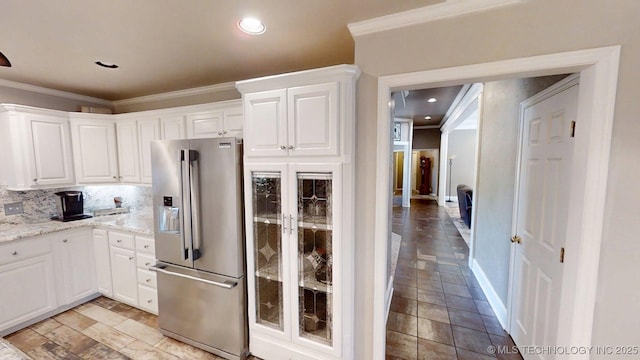 kitchen with crown molding, stainless steel refrigerator with ice dispenser, white cabinets, and decorative backsplash