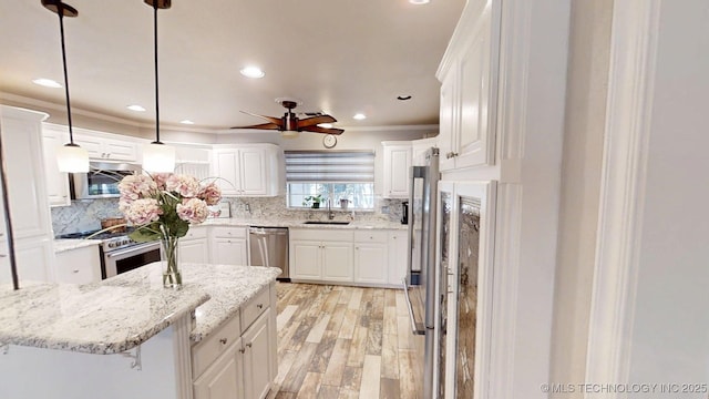 kitchen with decorative backsplash, ceiling fan, white cabinets, a sink, and stainless steel appliances