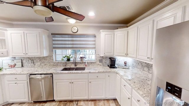 kitchen featuring white cabinetry, tasteful backsplash, a sink, light wood finished floors, and appliances with stainless steel finishes