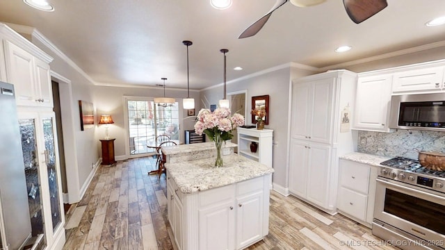 kitchen with stainless steel appliances, a center island, white cabinetry, and light wood-style floors