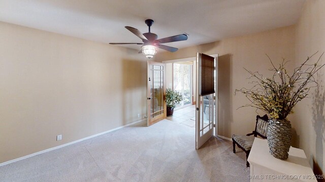 empty room featuring light colored carpet, a ceiling fan, baseboards, and french doors