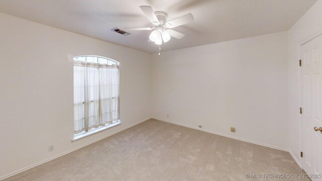unfurnished room featuring baseboards, ceiling fan, light colored carpet, and visible vents