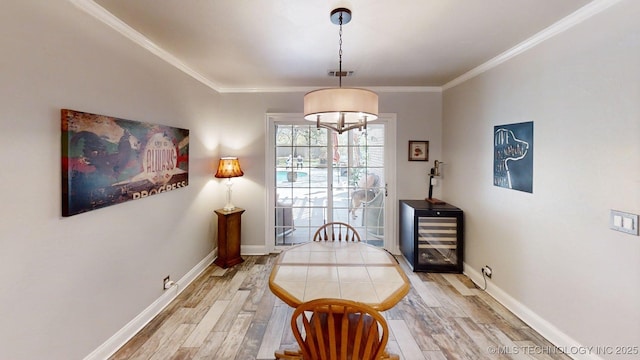 dining space featuring baseboards, ornamental molding, light wood-style flooring, and beverage cooler