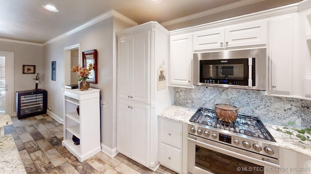 kitchen featuring stainless steel appliances, light stone countertops, white cabinetry, and tasteful backsplash