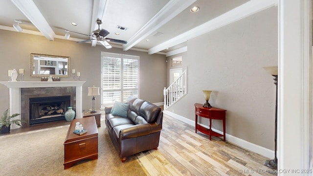 living room featuring a ceiling fan, beam ceiling, wood finished floors, baseboards, and ornamental molding
