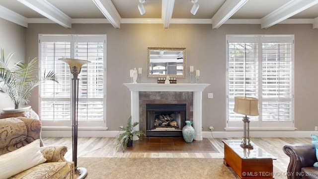 living room with crown molding, a tiled fireplace, baseboards, wood finished floors, and beamed ceiling