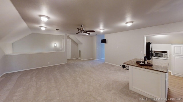 additional living space featuring a ceiling fan, baseboards, vaulted ceiling, and light carpet