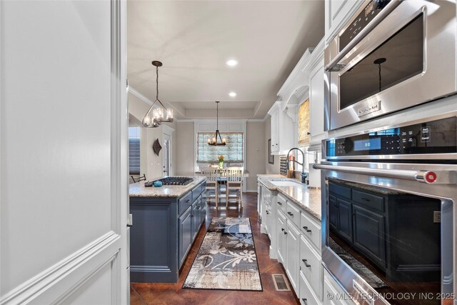12330 S Ash Ave, Jenks, OK 74037 - kitchen featuring stainless steel appliances, white cabinetry, a sink, light stone counters, and a chandelier