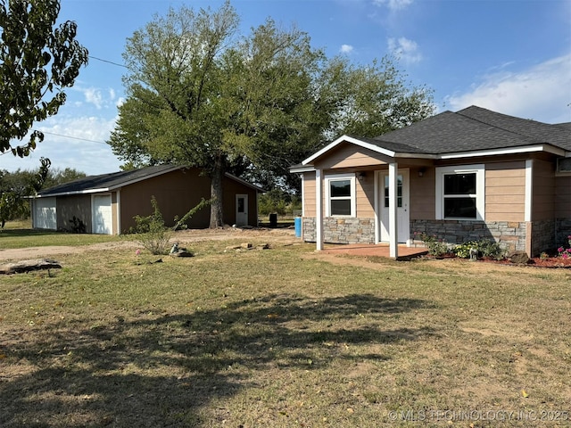 view of front of property featuring a shingled roof, a front lawn, and stone siding