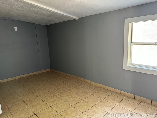unfurnished room with light tile patterned flooring, a textured ceiling, and baseboards