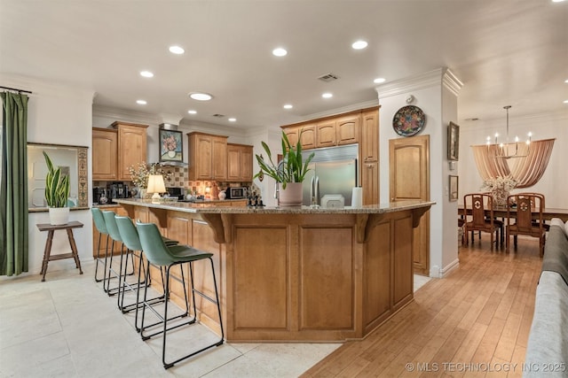 461 Cross Timbers Blvd, Sapulpa, OK 74066 - kitchen with recessed lighting, an inviting chandelier, a breakfast bar, decorative backsplash, and stainless steel built in refrigerator