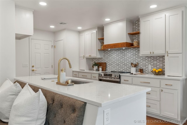 kitchen featuring open shelves, electric range, premium range hood, white cabinets, and a sink