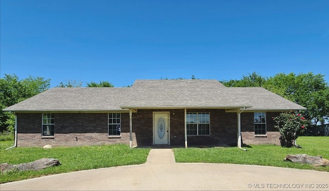 ranch-style home with roof with shingles, a front yard, and brick siding