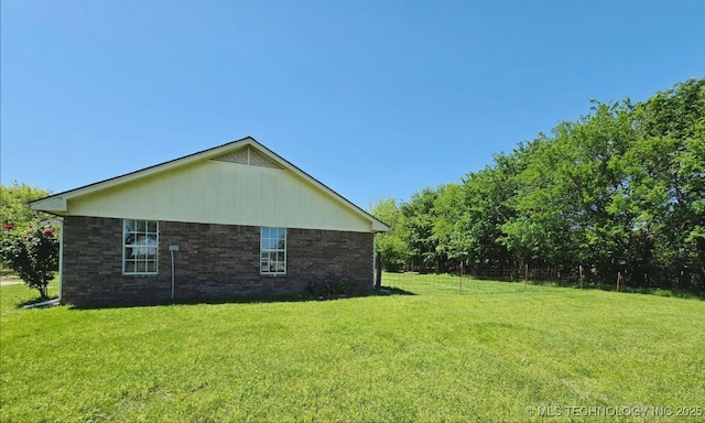view of side of home with brick siding and a yard