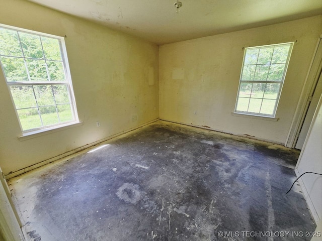 empty room featuring a wealth of natural light and unfinished concrete flooring