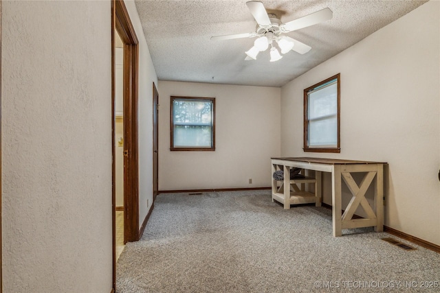 spare room featuring a ceiling fan, carpet flooring, a textured ceiling, and visible vents