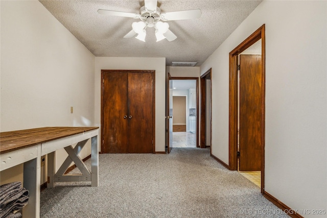 interior space featuring a textured ceiling, carpet flooring, a ceiling fan, and visible vents