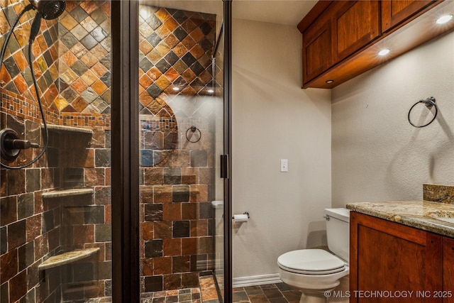 bathroom with toilet, vanity, stone finish flooring, baseboards, and a stall shower