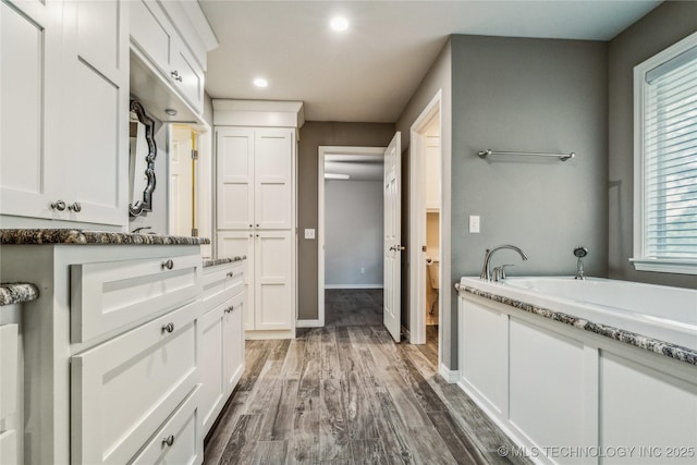 21083 Stick Ross Mountain Rd, Tahlequah, OK 74464 - bathroom with a bath, vanity, wood finished floors, recessed lighting, and baseboards