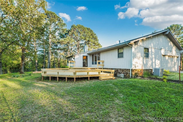 rear view of house featuring central AC, a chimney, a deck, and a lawn