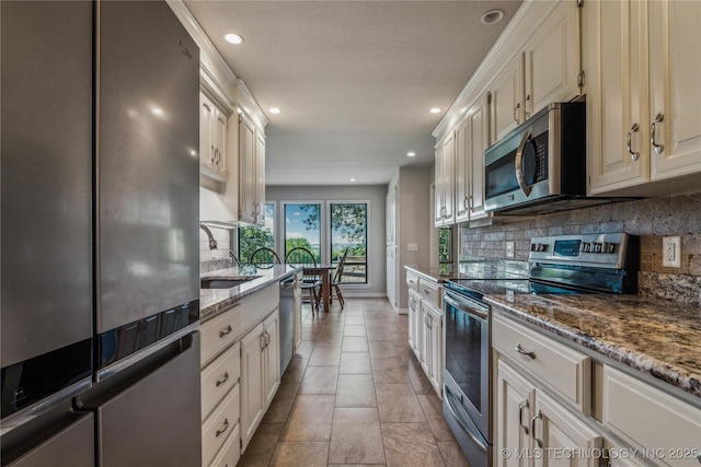 kitchen with stainless steel appliances, a sink, tasteful backsplash, recessed lighting, and light stone counters