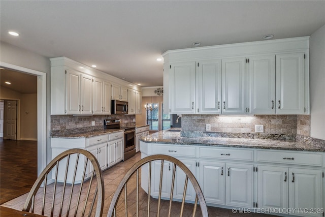 kitchen with tasteful backsplash, a sink, white cabinetry, stone counters, and appliances with stainless steel finishes