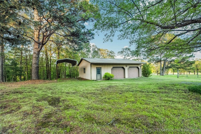 exterior space with a garage, a detached carport, and an outbuilding