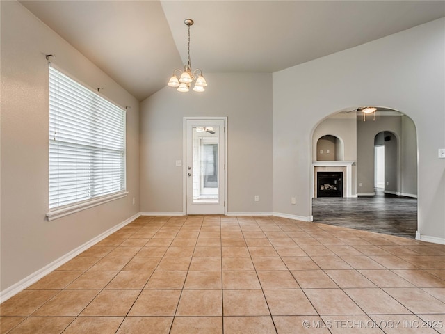 12520 S Birch Ave, Jenks, OK 74037 - spare room with healthy amount of natural light, lofted ceiling, light tile patterned floors, arched walkways, and a fireplace
