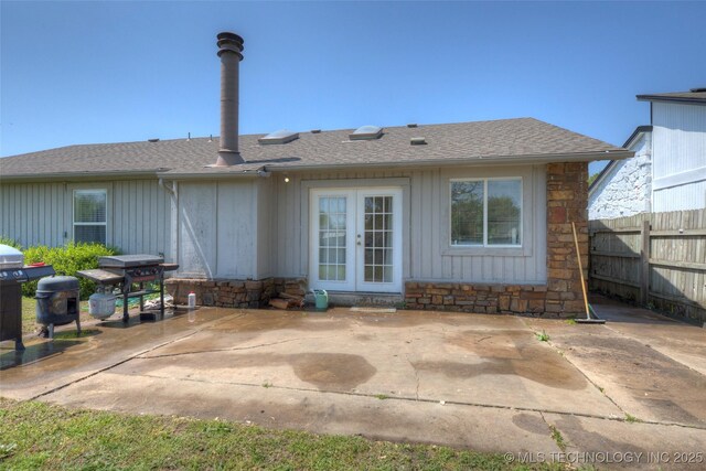 3249 S 138th E Ave, Tulsa, OK 74134 - rear view of property with stone siding, french doors, fence, a patio, and roof with shingles