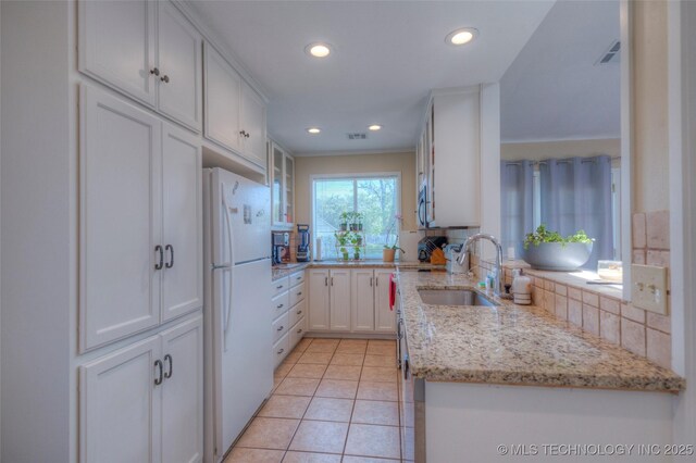 3249 S 138th E Ave, Tulsa, OK 74134 - kitchen with a sink, freestanding refrigerator, glass insert cabinets, light stone countertops, and light tile patterned floors